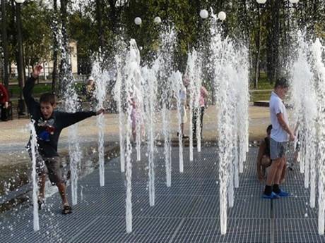 Several children are bouncing on the steel grating fountain drainage.