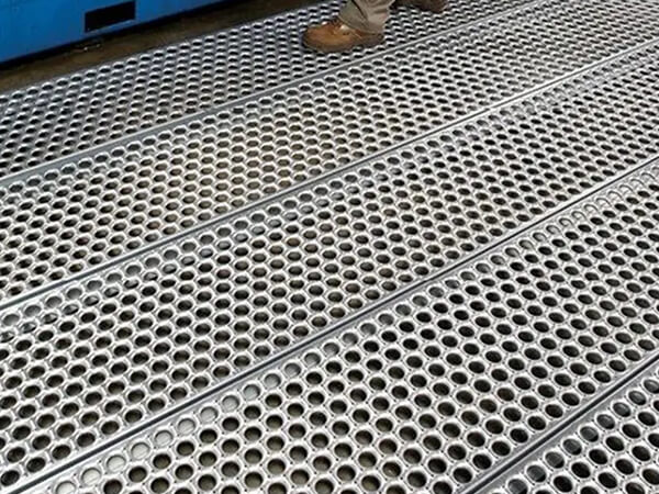 A worker is operating machine on the perforated steel grating flooring.