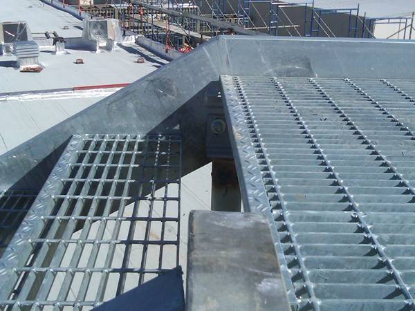 Stair treads with checker plate nosing are installed on the platform grating.