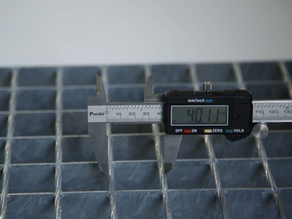 A worker is testing the cross bar pitch of steel bar grating.