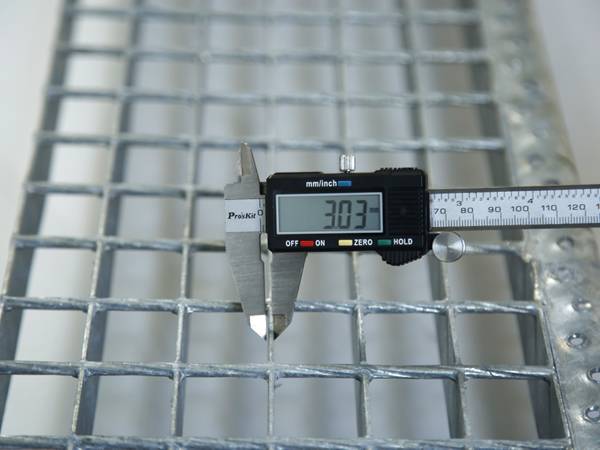 A worker is testing the aperture size of steel grating