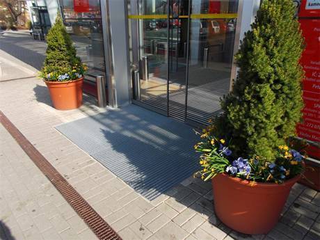 Steel grating entrance door mat placed in front of a shop door.