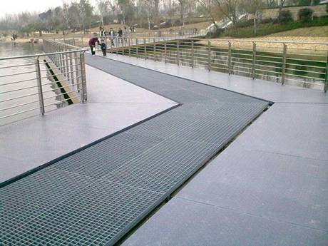 An old man with a child is playing on  steel grating walkway of river in park.