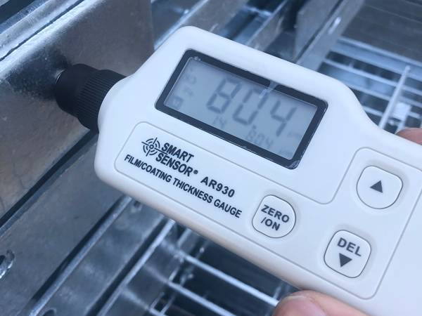 A worker is testing zinc coating of steel grating