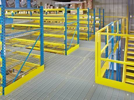 Steel grating warehouse racks with vertical blue brackets and horizontal yellow brackets.